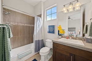 Ensuite bathroom with toilet, vanity, shower / bath combo with shower curtain, ensuite bath, and ceiling fan
