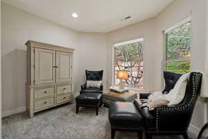 Living area featuring light carpet, baseboards, visible vents, and recessed lighting