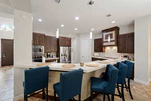 Kitchen featuring decorative backsplash, light countertops, a breakfast bar area, and appliances with stainless steel finishes