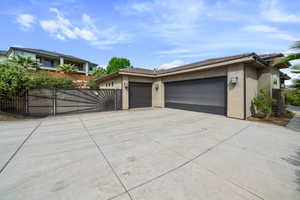View of front facade featuring stucco siding, an attached garage, concrete driveway, and a gate