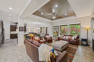 Living room featuring a tray ceiling, baseboards, ceiling fan, and recessed lighting