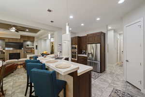 Kitchen with dark brown cabinets, a sink, light countertops, a kitchen bar, and appliances with stainless steel finishes