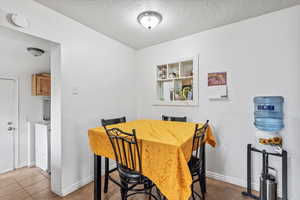 Dining area with a textured ceiling, tile patterned floors, and baseboards