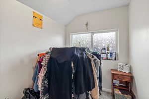 Walk in closet with vaulted ceiling and carpet