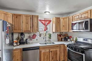 Kitchen featuring stainless steel appliances, light countertops, a sink, and a textured ceiling