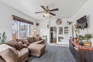 Carpeted living room with visible vents, a textured ceiling, and ceiling fan