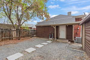 Back of property with fence private yard, roof with shingles, and central air condition unit