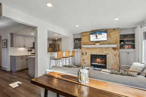 Living room featuring a fireplace, built in features, dark wood-style floors, and recessed lighting