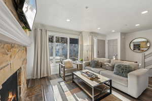 Living area featuring recessed lighting, a stone fireplace, baseboards, and wood finished floors