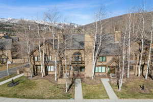 View of front of home with a front lawn, a mountain view, and a balcony