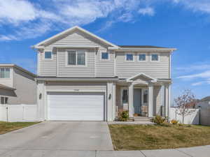 Traditional home with a front lawn, a gate, driveway, fence, and an attached garage