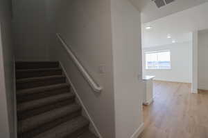 Staircase with visible vents, baseboards, wood finished floors, and recessed lighting