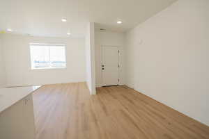 Empty room featuring visible vents, light wood-style flooring, baseboards, and recessed lighting