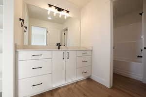 Bathroom featuring wood finished floors, vanity, and baseboards
