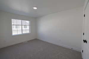 Unfurnished room featuring carpet floors, visible vents, and baseboards