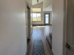 Front entry way featuring lofted ceiling, baseboards, wood finished floors, and attic access