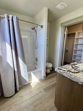 Master Full bath with toilet, visible vents, shower / tub combo with curtain, wood finished floors, and vanity walk in closet