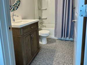 Full bath featuring shower / bath combo, toilet, visible vents, speckled floor, and vanity