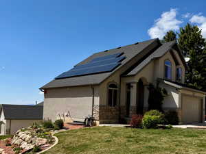 View of property exterior featuring stucco siding, solar panels, and a yard
