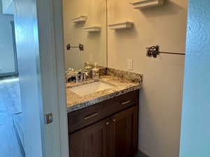 Bathroom with baseboards, wood finished floors, vanity, and a textured ceiling