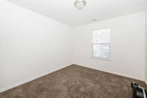 Empty room featuring visible vents, carpet flooring, and baseboards