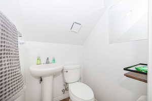 Bathroom featuring vaulted ceiling, a sink, and toilet