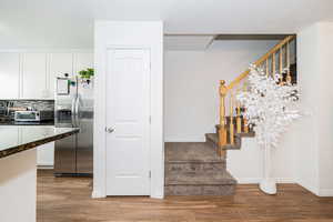 Stairs with a toaster, wood finished floors, and baseboards