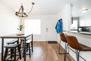 Dining room featuring light wood-type flooring, baseboards, and a notable chandelier