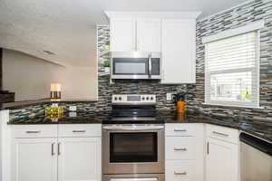 Kitchen featuring stainless steel appliances, backsplash, and white cabinetry