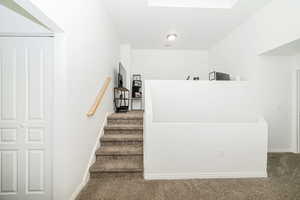 Staircase to third level with visible vents, baseboards, and carpet flooring