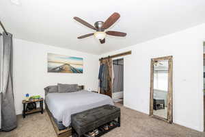 Bedroom with a barn door, carpet flooring, baseboards, and a ceiling fan