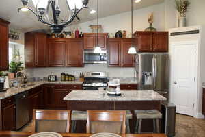 Kitchen featuring a sink, a chandelier, stainless steel appliances, hanging light fixtures, and lofted ceiling