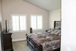 Bedroom with multiple windows, baseboards, vaulted ceiling, and carpet floors