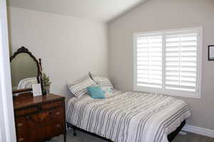 Carpeted bedroom featuring baseboards and vaulted ceiling