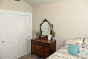 Carpeted bedroom with a closet and lofted ceiling