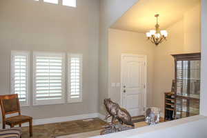 Entryway with an inviting chandelier, a towering ceiling, plenty of natural light, and baseboards