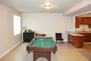 Playroom featuring baseboards, a sink, billiards, and finished concrete floors