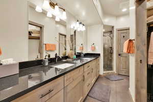 Full bath with tile patterned flooring, a sink, double vanity, and a stall shower