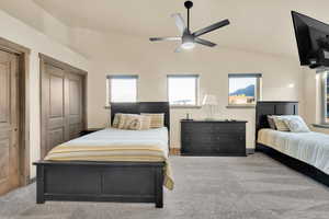 Carpeted bedroom with lofted ceiling, a ceiling fan, and two closets