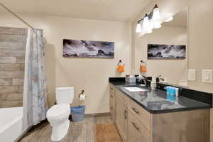 Bathroom featuring vanity, toilet, baseboards, shower / tub combo with curtain, and wood tiled floor