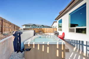 featuring grilling area, a fenced backyard, and a hot tub