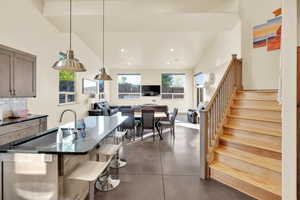 Kitchen with recessed lighting, concrete flooring, dark stone counters, tasteful backsplash, and a breakfast bar area