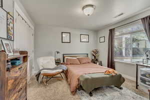 Carpeted bedroom featuring baseboards and visible vents