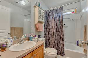 Full bathroom with visible vents, toilet, vanity, and shower / bathtub combination with curtain