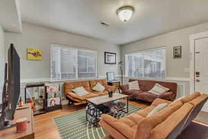 Living room featuring a wainscoted wall, wood finished floors, and visible vents