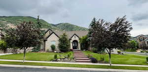 View of front facade with stone siding, a front yard, and a mountain view
