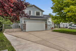 Split level home with a gate, driveway, fence, a garage, and a front yard