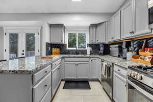 Kitchen featuring gray cabinets, a peninsula, stainless steel appliances, and a sink