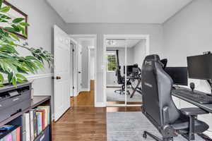Office with wood finished floors, baseboards, and ornamental molding