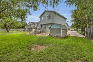 Back of house featuring a lawn, fence, a deck, and stairway
